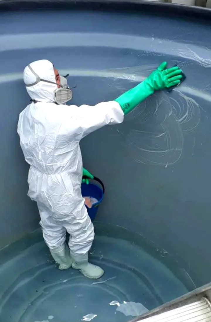 Técnico limpiando el interior de un tanque de agua